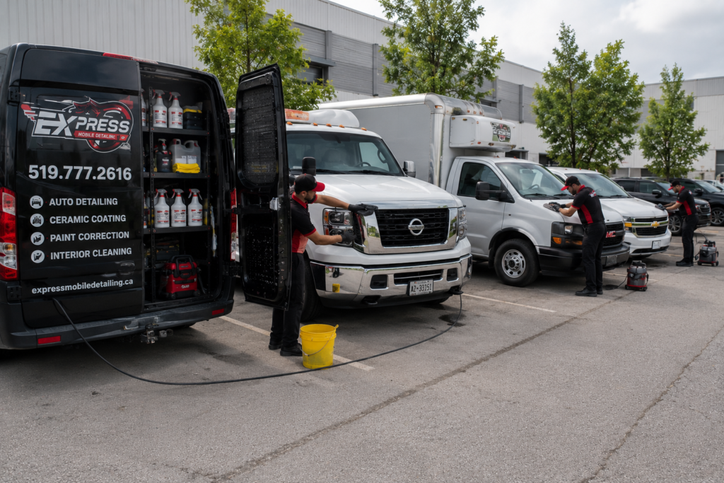 Mobile fleet detailing team cleaning multiple commercial vans and service vehicles at a business facility in Canada