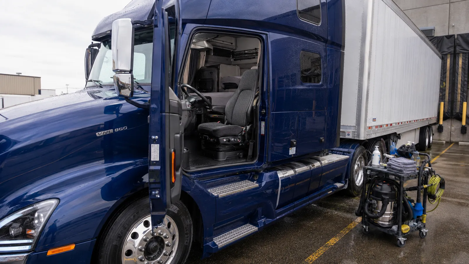 A blue tractor unit and trailer being detailed in a yard