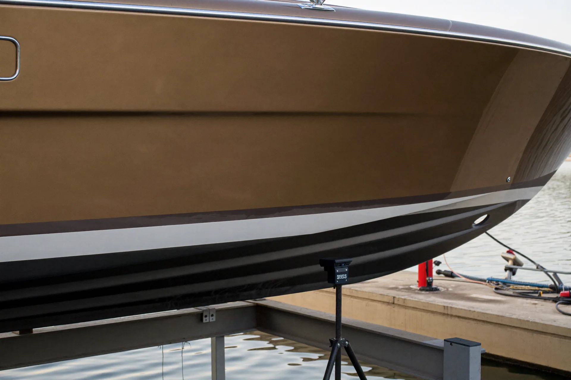 Wide mobile-detailing view on a bronze centre-console boat at a dry-dock cradle during boat detailing